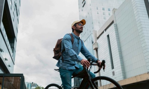 A man with a backpack riding a bicycle in the city.